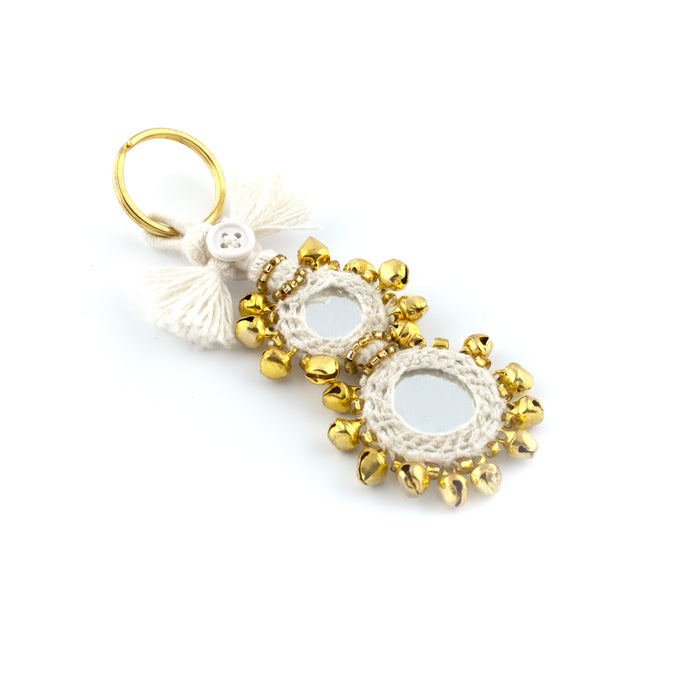 Nyckelring tillverkad av vitt garn, pärlor, speglar och bjällror. Med ring för fastsättning.  Längd exkl. ring: 11 cm.
