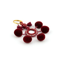 Ladda upp bild till galleriet Nyckelring i vinrött tillverkad av pompoms, garn, pärlor och spegel.  Med ring för fastsättning.  Längd exkl. ring: 10,5 cm.
