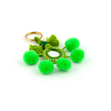 Ladda upp bild till galleriet Nyckelring i grönt tillverkad av pompoms, garn, pärlor och spegel.  Med ring för fastsättning.  Längd exkl. ring: 10,5 cm.
