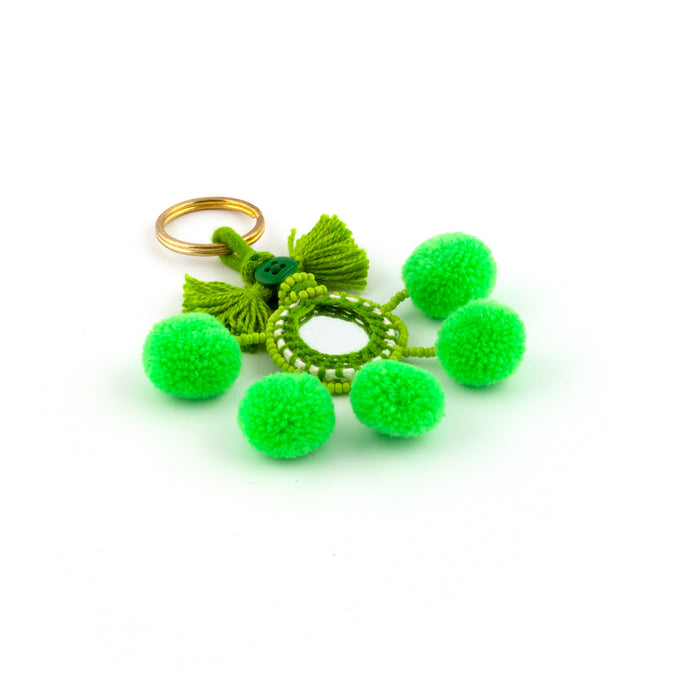 Nyckelring i grönt tillverkad av pompoms, garn, pärlor och spegel.  Med ring för fastsättning.  Längd exkl. ring: 10,5 cm.