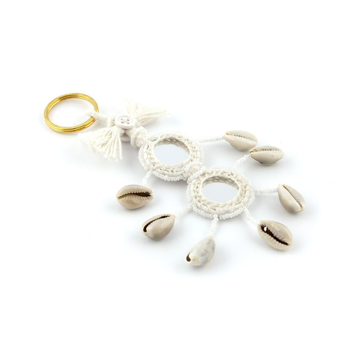 Nyckelring i vitt tillverkad av garn, pärlor, snäckor och speglar. Med ring för fastsättning.  Längd exkl. ring: 14 cm.