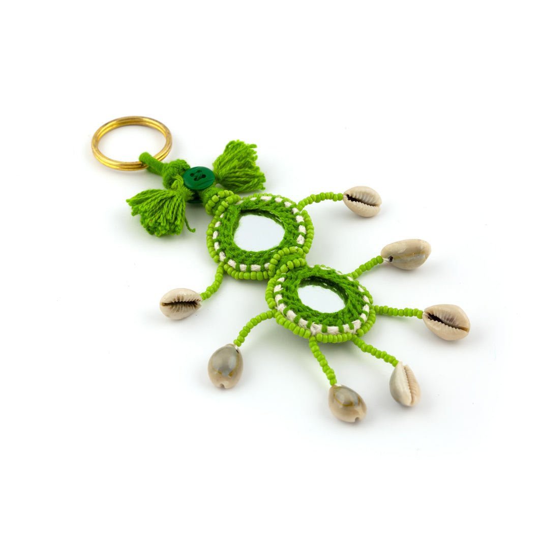 Nyckelring i grönt tillverkad av garn, pärlor, snäckor och speglar. Med ring för fastsättning.  Längd exkl. ring: 14 cm.