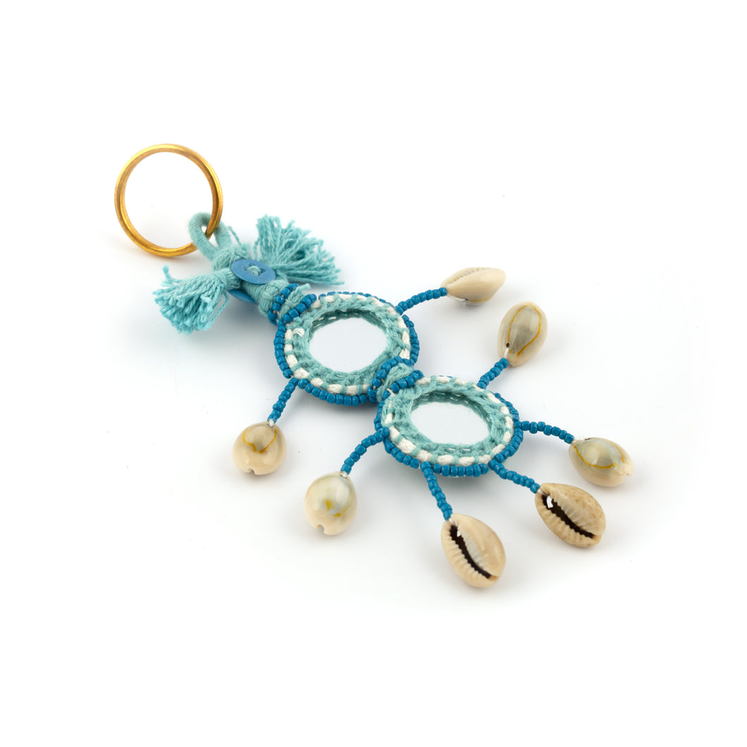 Nyckelring i blått tillverkad av garn, pärlor, snäckor och speglar. Med ring för fastsättning.  Längd exkl. ring: 14 cm.