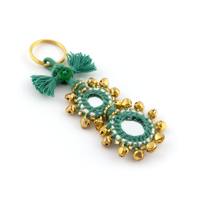 Nyckelring tillverkad av grönt garn, pärlor, speglar och bjällror. Med ring för fastsättning.  Längd exkl. ring: 11 cm.