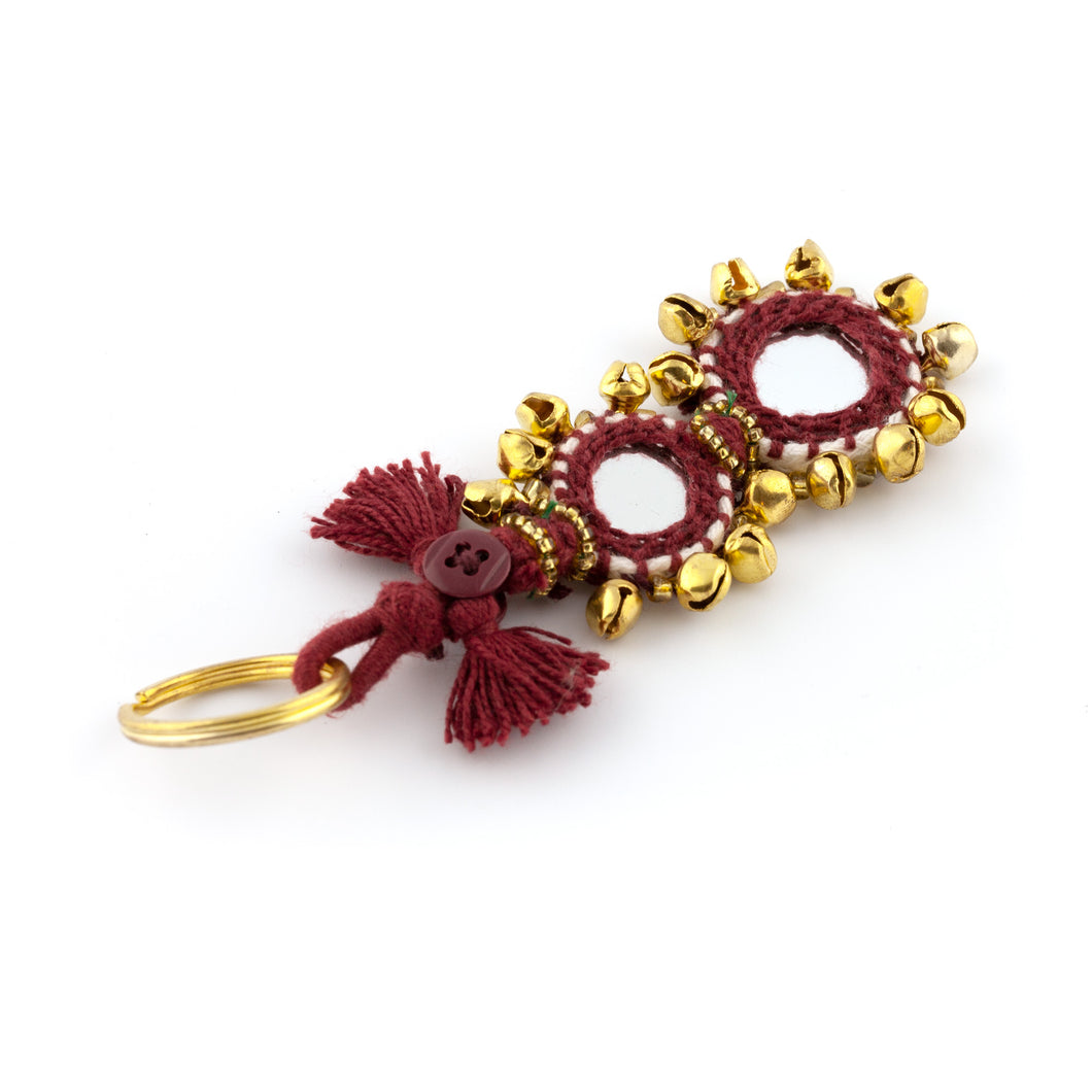 Nyckelring tillverkad av vinrött garn, pärlor, speglar och bjällror. Med ring för fastsättning.  Längd exkl. ring: 11 cm.