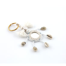 Ladda upp bild till galleriet Nyckelring tillverkad av vitt garn, pärlor, speglar och snäckor.  Med ring för fastsättning.  Längd exkl. ring: 13,5 cm.
