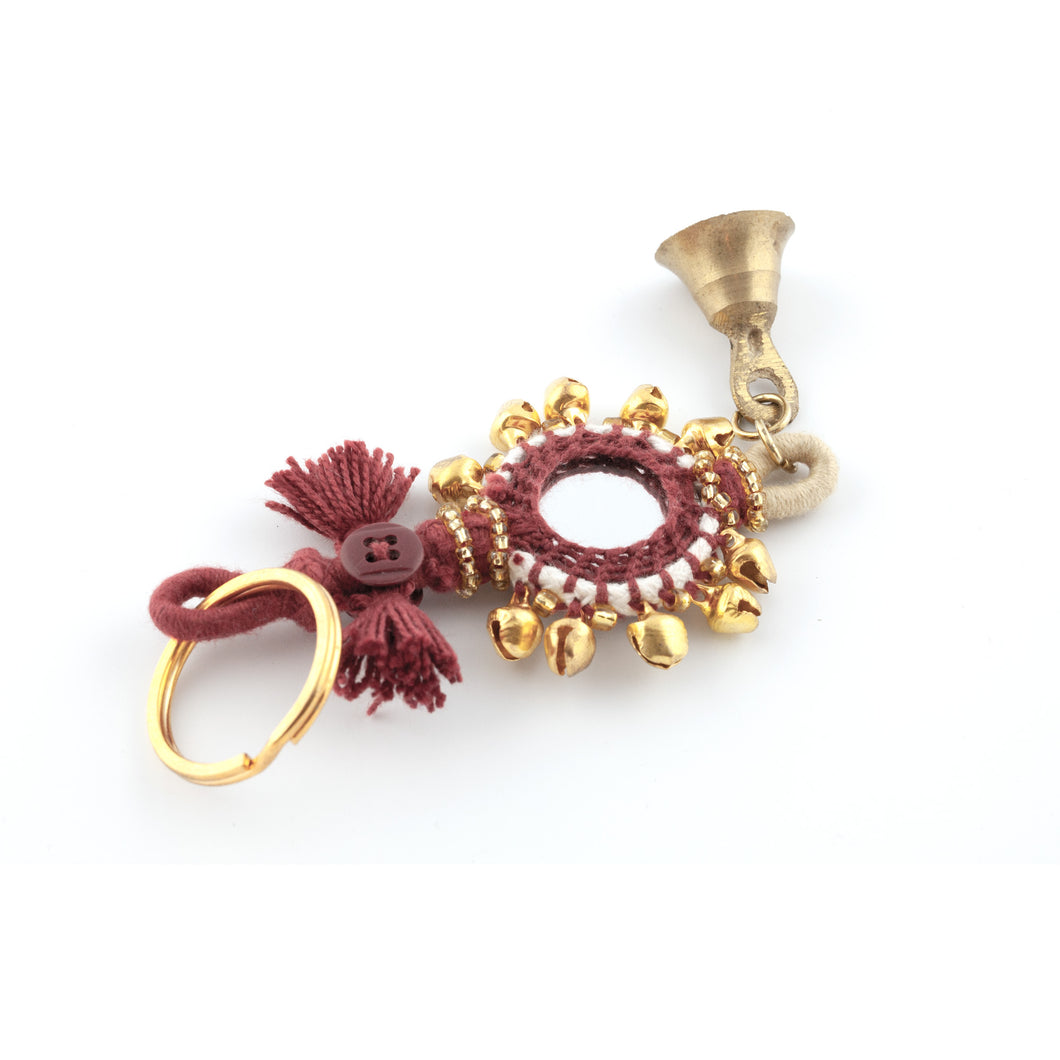 Nyckelring tillverkad av vinrött garn, pärlor, speglar och bjällror.  Med ring för fastsättning.  Längd exkl. ring: 13,5 cm.