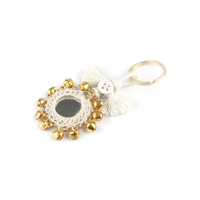 Nyckelring tillverkad av vitt garn, pärlor, speglar och bjällror. Med ring för fastsättning.  Längd exkl. ring: 8,5 cm.