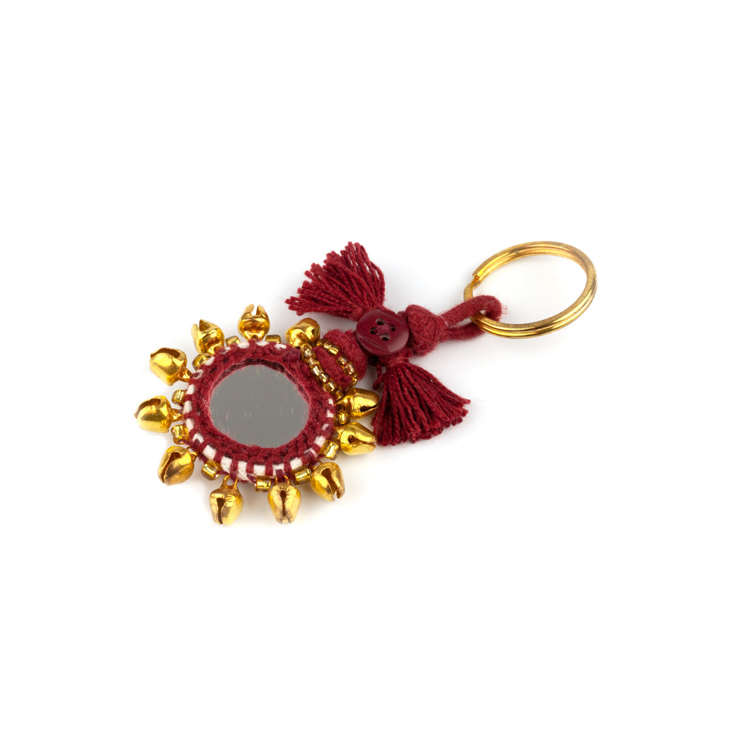 Nyckelring tillverkad av vinrött garn, pärlor, speglar och bjällror. Med ring för fastsättning.  Längd exkl. ring: 8,5 cm.