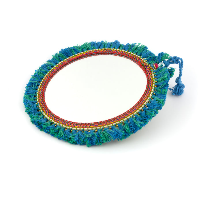 Tvåsidig spegel dekorerad med garn och pärlor. Med snöre för upphängning.  Färg: grön/blå  Storlek: 20 cm i diameter.